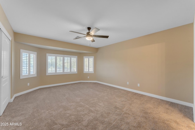 spare room with carpet floors, a ceiling fan, and baseboards