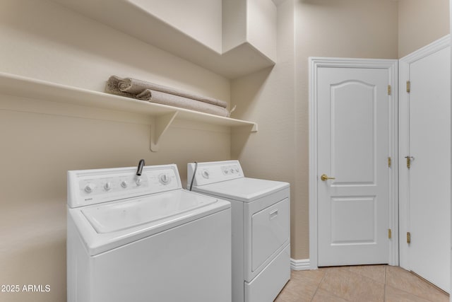 washroom featuring washing machine and clothes dryer, light tile patterned flooring, and laundry area