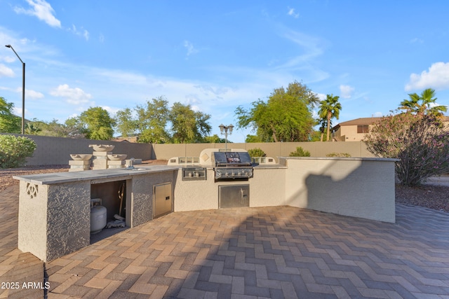view of patio with fence, exterior kitchen, and grilling area