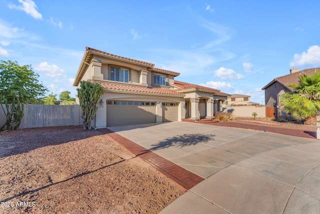 mediterranean / spanish-style home with a garage, fence, stucco siding, a tiled roof, and driveway