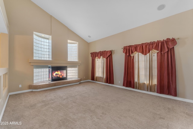 unfurnished living room featuring high vaulted ceiling, baseboards, carpet, and a multi sided fireplace