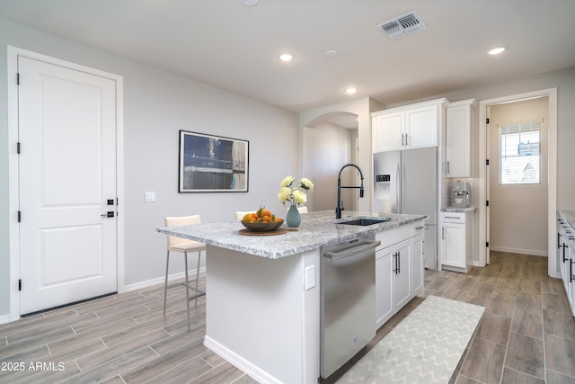 kitchen with sink, stainless steel dishwasher, a kitchen island with sink, and white cabinetry