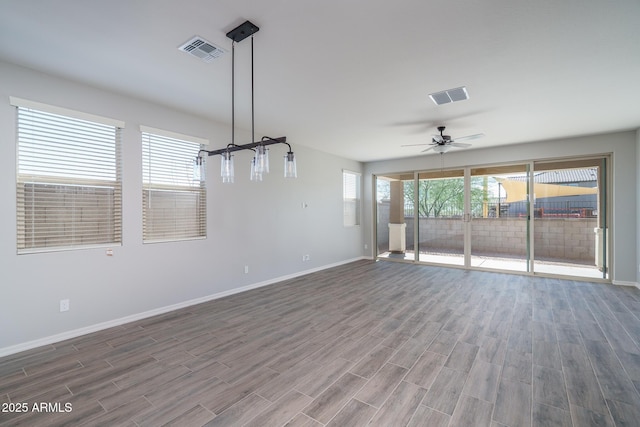 unfurnished room featuring a wealth of natural light, ceiling fan, and dark hardwood / wood-style floors