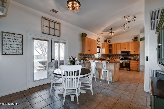 tiled dining space with french doors, visible vents, vaulted ceiling, and baseboards