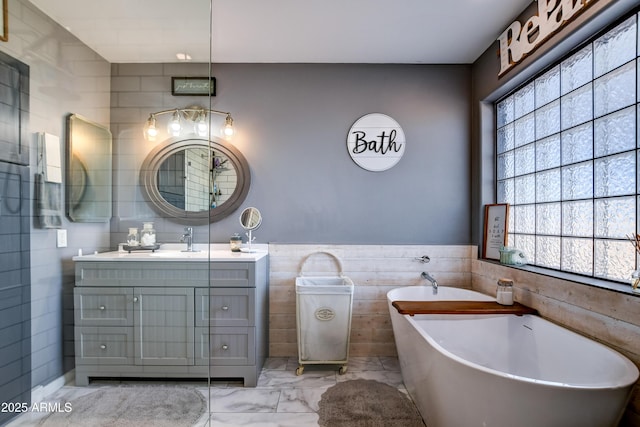 full bath with marble finish floor, a soaking tub, plenty of natural light, and vanity