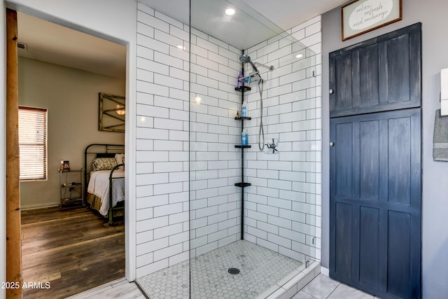 ensuite bathroom with wood finished floors, tiled shower, visible vents, and ensuite bathroom