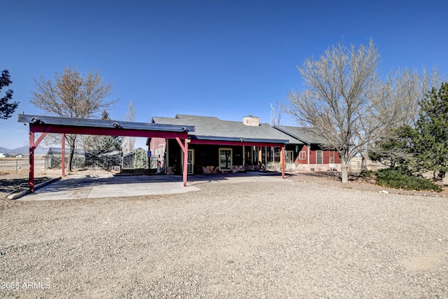 view of front facade featuring a carport, gravel driveway, and a chimney