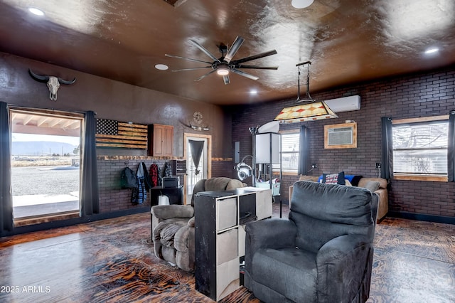 living room with a wall unit AC, brick wall, ceiling fan, and a wall mounted air conditioner