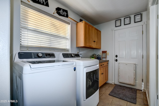 laundry area with cabinet space, light tile patterned floors, and washer and dryer