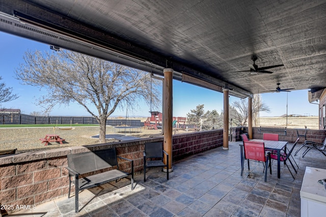 view of patio featuring fence, outdoor dining area, and a ceiling fan