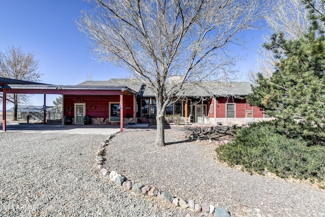 rear view of property featuring stone siding and an attached carport