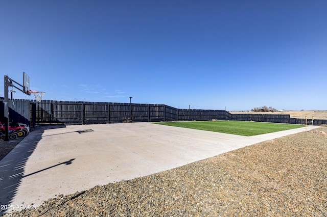 view of basketball court featuring a yard, community basketball court, and fence