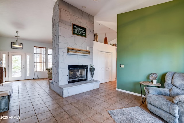 living area with tile patterned flooring, a fireplace, a towering ceiling, and baseboards