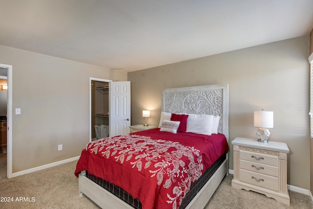 bedroom with a walk in closet, a closet, and light colored carpet