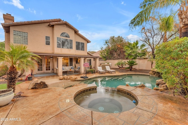 view of swimming pool featuring french doors, a pool with connected hot tub, a fenced backyard, and a patio area