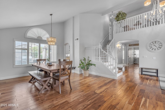 dining room featuring stairs, wood finished floors, arched walkways, and a chandelier