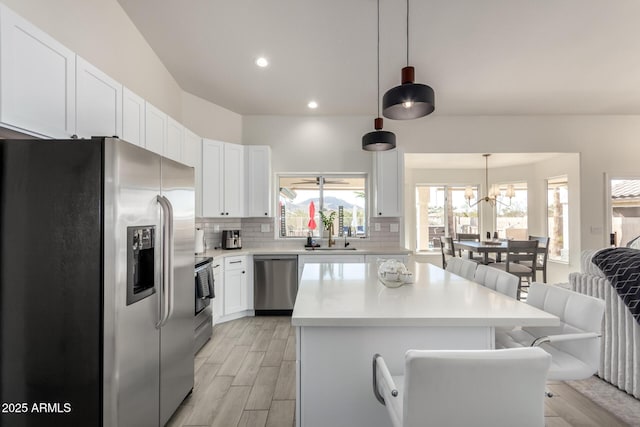 kitchen with a kitchen breakfast bar, white cabinetry, decorative light fixtures, and appliances with stainless steel finishes