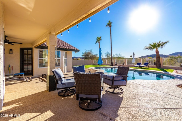 view of patio / terrace with a fenced in pool, ceiling fan, and a mountain view