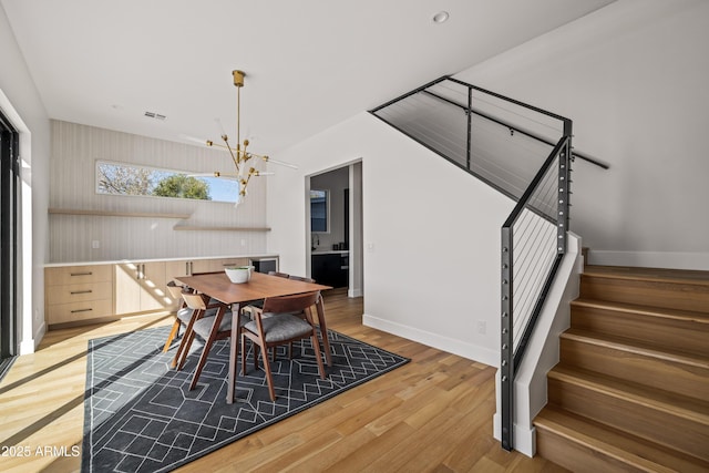 dining room with visible vents, baseboards, stairway, light wood-style flooring, and an inviting chandelier