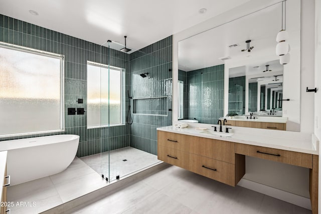 full bath featuring tile patterned floors, a freestanding tub, a tile shower, tile walls, and vanity