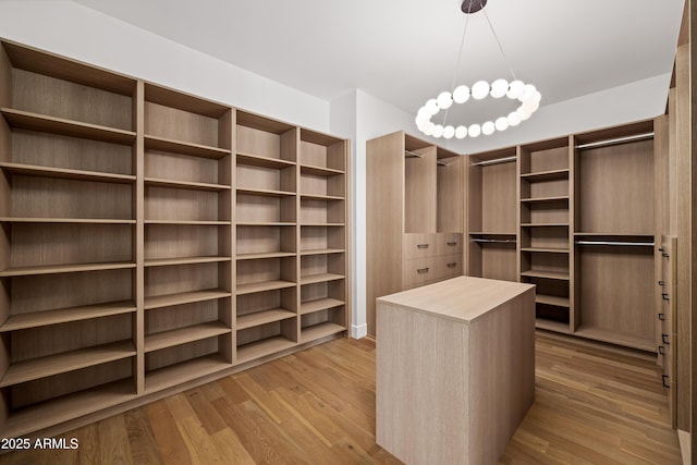 walk in closet featuring light wood-type flooring and a chandelier