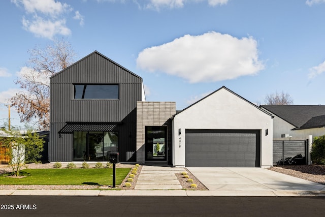 modern inspired farmhouse with a front yard, concrete driveway, an attached garage, and fence