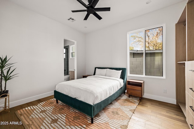 bedroom with visible vents, baseboards, light wood-style flooring, and ensuite bathroom