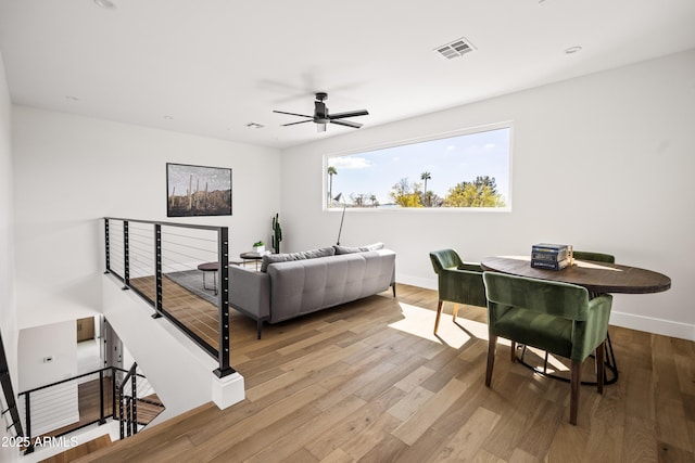 living area featuring a ceiling fan, visible vents, wood finished floors, and baseboards