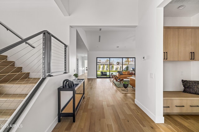 hallway featuring stairs, light wood-style floors, and baseboards