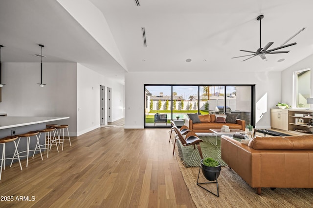 living room with baseboards, wood-type flooring, high vaulted ceiling, and ceiling fan