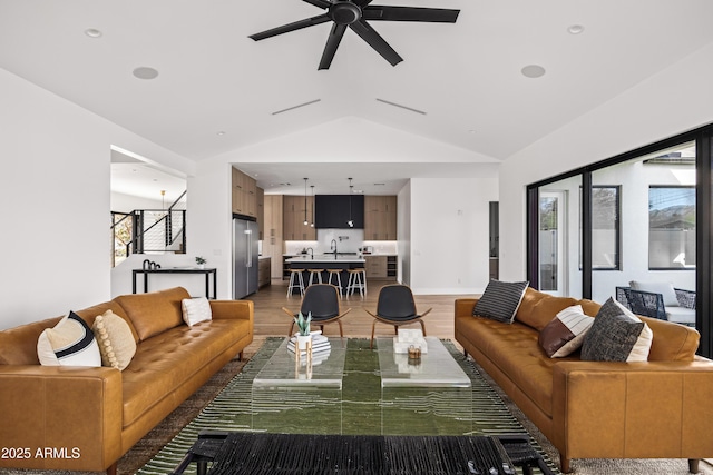 living room featuring baseboards, light wood-style flooring, a ceiling fan, and vaulted ceiling