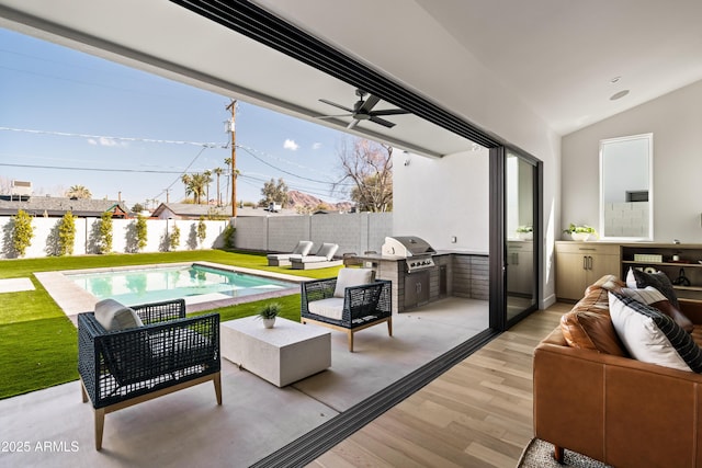 view of patio with grilling area, ceiling fan, an outdoor hangout area, a fenced backyard, and an outdoor kitchen