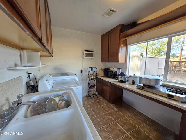 kitchen featuring stainless steel gas cooktop, sink, dark tile patterned floors, a wall mounted AC, and washer and dryer