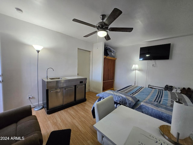 bedroom featuring ceiling fan, sink, and light hardwood / wood-style floors