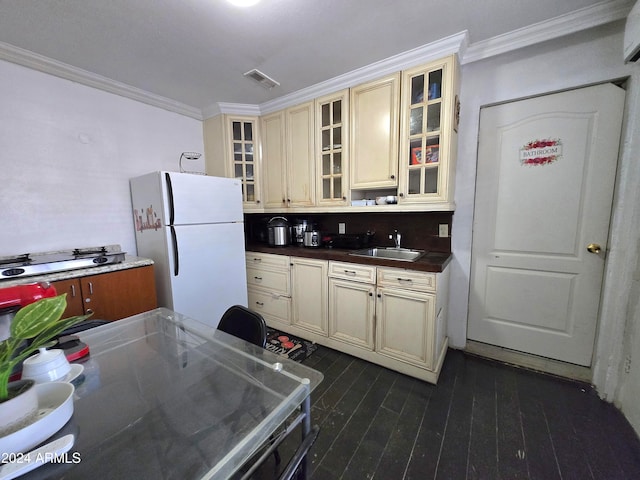 kitchen with ornamental molding, sink, cream cabinetry, and white refrigerator