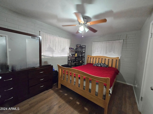 bedroom featuring ceiling fan, brick wall, and dark hardwood / wood-style flooring