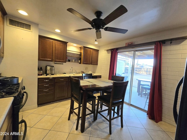 kitchen featuring light tile patterned flooring, ceiling fan, black range, and sink