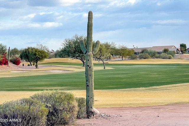 view of property's community featuring view of golf course and a lawn