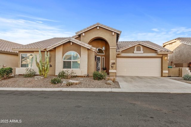 mediterranean / spanish-style house with a garage, a tile roof, concrete driveway, and stucco siding