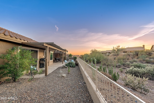 yard at dusk with a patio area and a fenced backyard