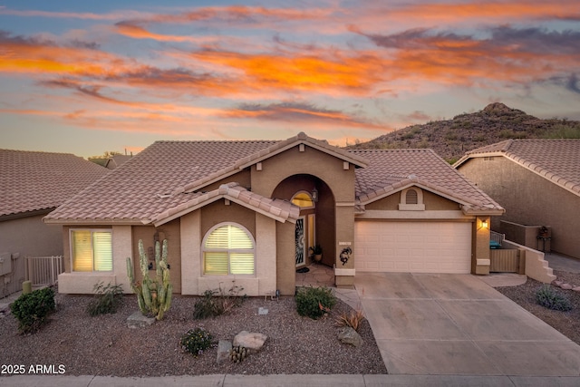 mediterranean / spanish-style house featuring concrete driveway, an attached garage, a tiled roof, and stucco siding