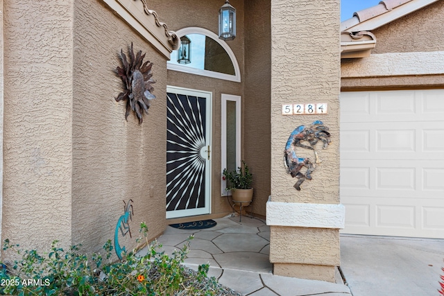 doorway to property featuring a garage and stucco siding