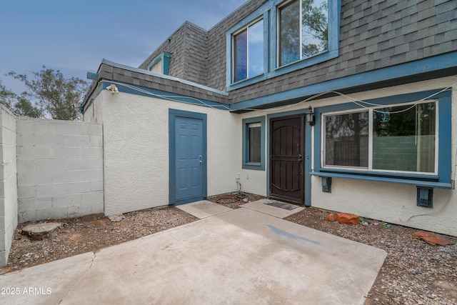 8125 N 32nd Dr, Phoenix, AZ 85051 - entrance to property featuring mansard roof, stucco siding, a shingled roof, and a patio