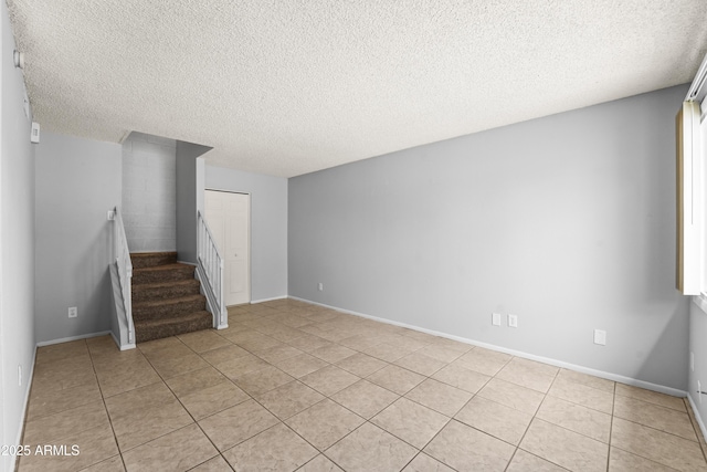 8125 N 32nd Dr, Phoenix, AZ 85051 - empty room featuring a textured ceiling, light tile patterned floors, stairway, and baseboards