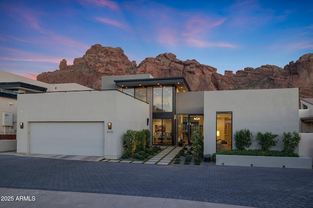 contemporary home with an attached garage, decorative driveway, and stucco siding