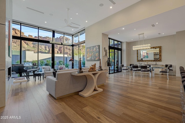 living area featuring a wall of windows, recessed lighting, a towering ceiling, and hardwood / wood-style flooring