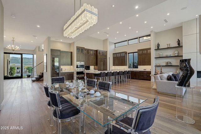 dining space featuring hardwood / wood-style floors, recessed lighting, a towering ceiling, and an inviting chandelier