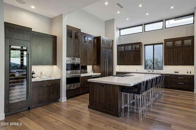 kitchen featuring a kitchen breakfast bar, dark wood-style floors, visible vents, and a center island