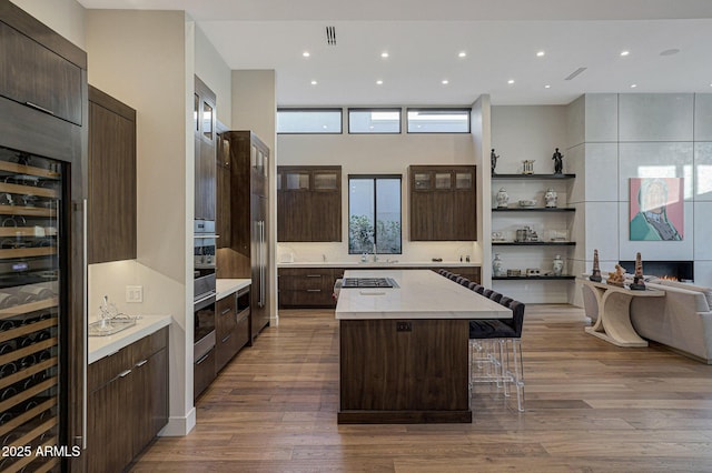 kitchen featuring a breakfast bar, modern cabinets, a kitchen island, dark brown cabinets, and wood finished floors