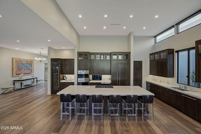 kitchen with a large island, a kitchen bar, dark wood finished floors, and a sink